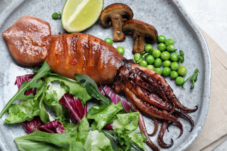 Tasty grilled squid served on white table, top view