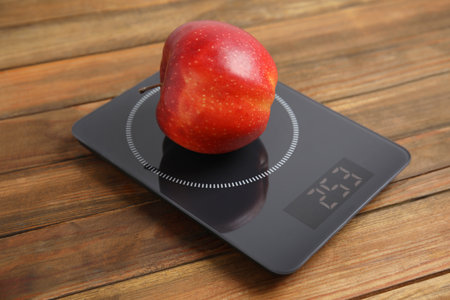 Ripe red apple and electronic scales on wooden tableの写真素材