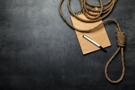 Rope noose and blank notebook with pen on gray table, flat lay. Space for textの写真素材