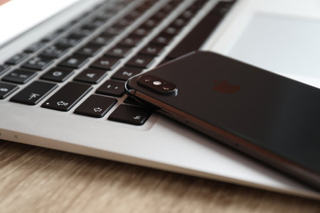 MYKOLAIV, UKRAINE - AUGUST 28, 2020: iPhone 11 and MacBook laptop on wooden table, closeupのeditorial素材