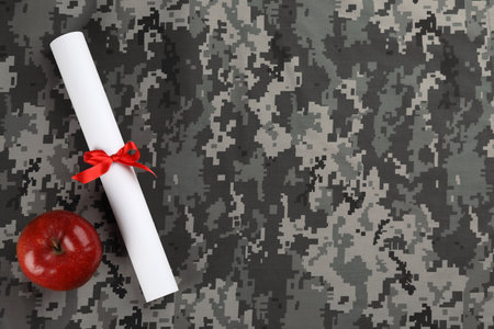 Apple and diploma on camouflage background, flat lay with space for text. military education conceptの写真素材