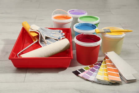 Buckets of paints, palette and decorator's tools on light wooden backgroundの写真素材