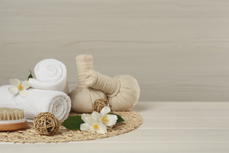 Composition with beautiful jasmine flowers, towels and herbal bags on white wooden table, space for textの写真素材
