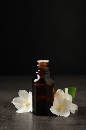 Essential oil and jasmine flowers on gray tableの写真素材