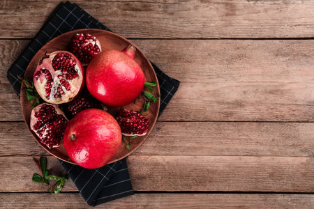 Delicious ripe pomegranates on wooden table, top view. Space for textの写真素材