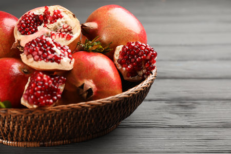 Delicious ripe pomegranates on gray wooden table, closeup. Space for textの写真素材
