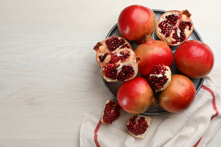Delicious ripe pomegranates on white wooden table, flat lay. Space for textの写真素材