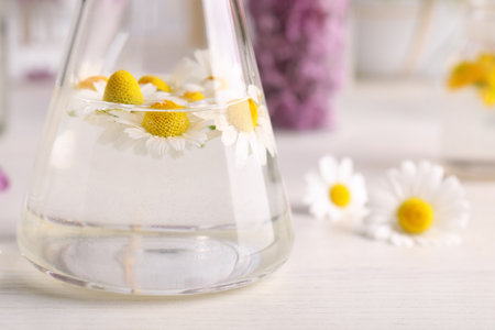 Flask with flowers on table, closeup. Extracting essential oils for perfumery and cosmeticsの写真素材