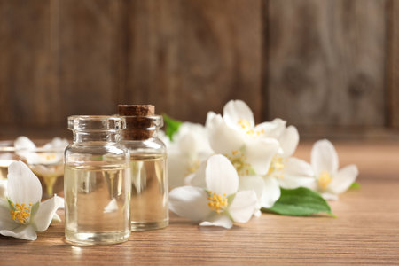 Jasmine essential oil and fresh flowers on wooden table, space for textの写真素材