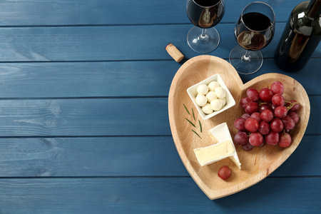 Flat lay composition with red wine and snacks on blue wooden table, space for textの写真素材