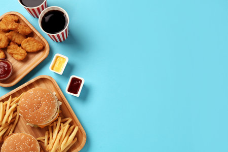 Different fast food on turquoise background, flat lay. Space for textの写真素材