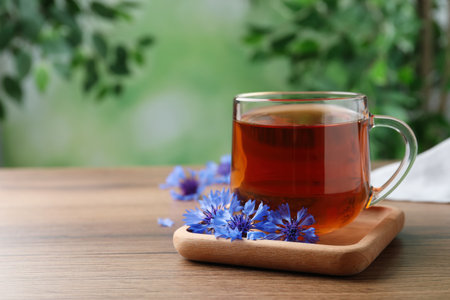 Glass cup of tea and cornflowers on wooden table. Space for textの写真素材