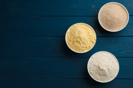 Different types of flours in bowls on blue wooden table, flat lay. Space for textの写真素材
