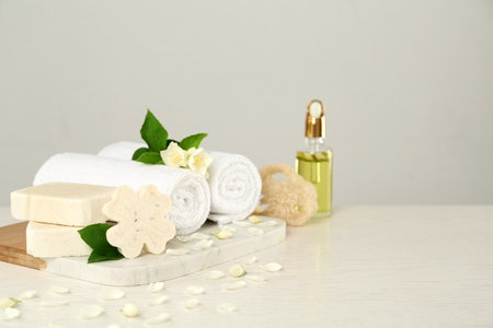 Beautiful jasmine flowers, towels and soap bars on white wooden table, space for textの写真素材