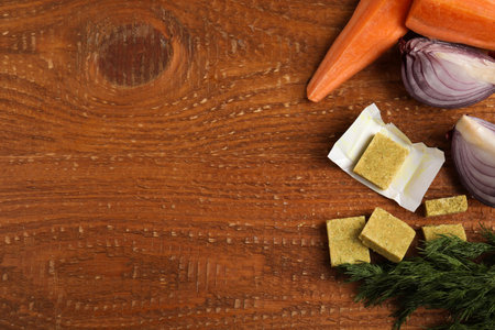 Bouillon cubes and other ingredients on wooden table, flat lay. Space for textの写真素材