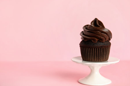 Dessert stand with delicious chocolate cupcake on pink background. Space for textの写真素材