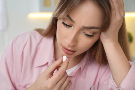 Young woman taking abortion pill on blurred backgroundの写真素材