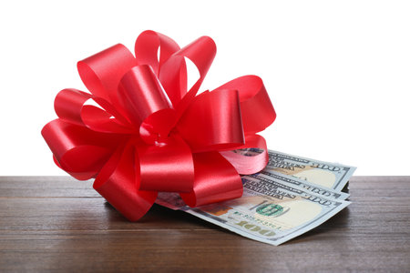 Dollar bills with red bow on wooden table against white backgroundの写真素材