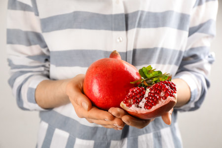 Woman holding ripe pomegranates on light background, closeupの写真素材