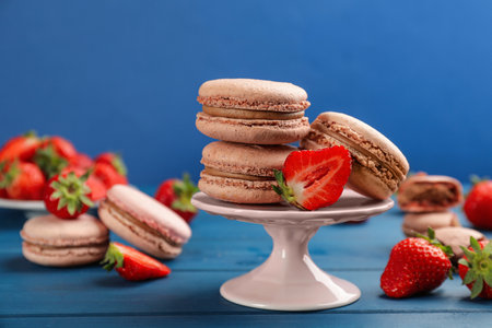 Delicious macarons and strawberries on blue wooden tableの写真素材
