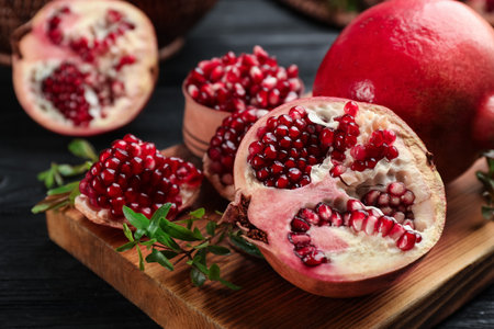 Delicious ripe pomegranates on black wooden table, closeupの写真素材