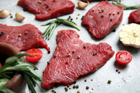 Fresh raw meat steaks and spices on light gray table, closeupの写真素材