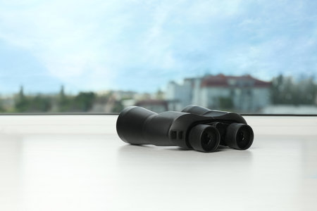 Black binoculars on white window sill. Space for textの写真素材