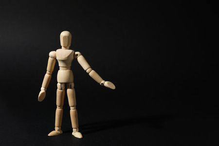 Wooden human model on black background, space for text. Mini mannequinの写真素材