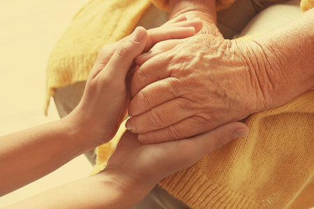 Helping hands on blurred background, closeup. Elderly care conceptの写真素材