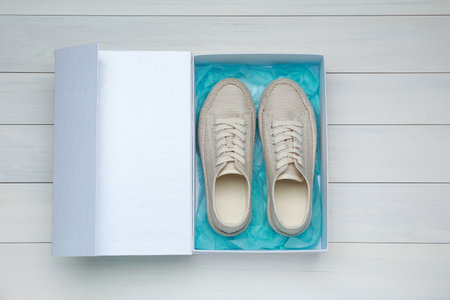 Pair of stylish sport shoes in box on white wooden background, top viewの写真素材