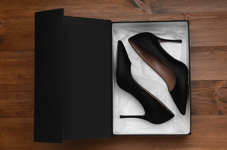 Pair of stylish shoes in black box on wooden background, top viewの写真素材
