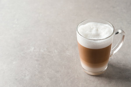Hot coffee with milk in glass cup on light table. Space for textの写真素材
