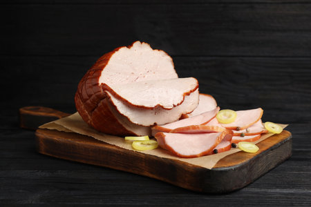 Delicious cut ham served on black wooden tableの写真素材
