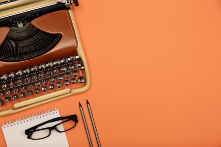 Vintage typewriter, glasses and stationery on coral background, flat lay. Space for textの写真素材