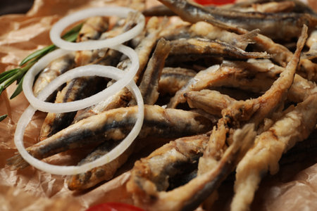 Delicious fried anchovies with onion rings served on table, closeupの写真素材