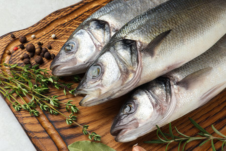 Tasty sea bass fish with spices on gray textured table, closeup