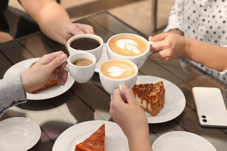 Friends drinking coffee at wooden table in outdoor cafe, closeupの写真素材