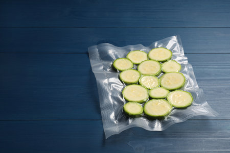 Plastic bag with cut zucchinis on blue wooden table. Space for textの写真素材