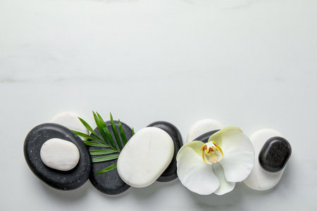 Flat lay composition with spa stones, orchid flower and leaf on white marble table. Space for textの写真素材