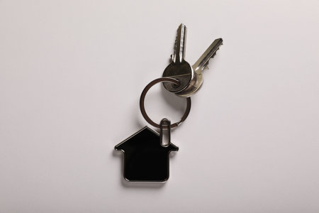 Keys with trinket in shape of house on white background, top view. real estate agent servicesの写真素材