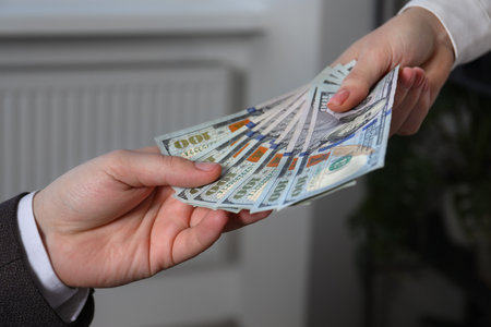 Woman giving money to man indoors, closeup. currency exchange