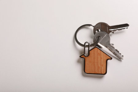 Keys with trinket in shape of house on white background, top view and space for text. real estate agent servicesの写真素材
