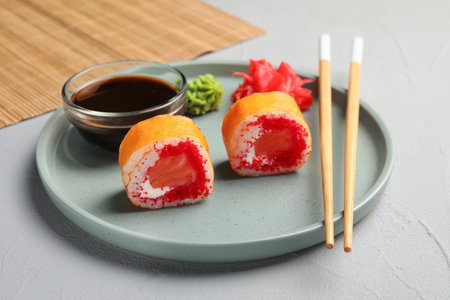 Delicious sushi rolls, soy sauce, wasabi, ginger and chopsticks on gray textured table, closeupの写真素材