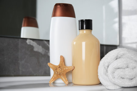 Bottles of shower gel and fresh towel with starfish on sink in bathroom. Space for textの写真素材