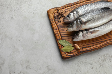 Tasty sea bass fish with spices on gray textured table, top view. Space for textの写真素材