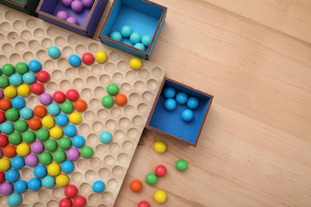 Wooden sorting board and boxes with colorful balls on table, flat lay. Montessori toyの写真素材