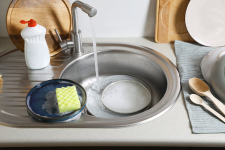 Washing plates and sponges in kitchen sinkの写真素材