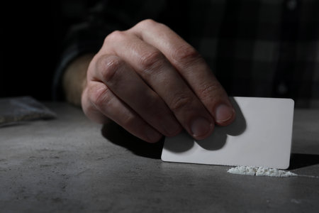 Addicted man preparing drugs for consumption at gray table, closeupの写真素材