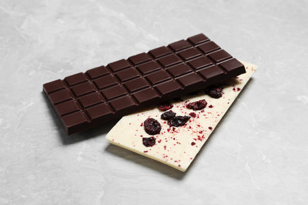 Different chocolate bars with freeze dried grapes on light marble tableの写真素材