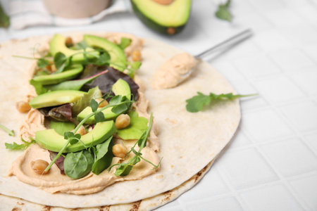Tortilla with hummus and vegetables on white table, closeup. Space for textの写真素材